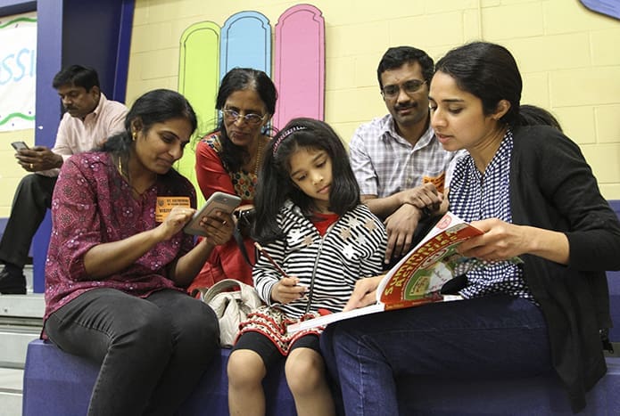 (Clockwise, from bottom right) Beno Varghese, her four-year-old daughter Rachel Abraham, Shylaja Sivaprakasam, Varghese’s mother-in-law Molly Abraham, and her husband Moby Abraham hung out in the gymnasium while the students were away for some 90 minutes competing in the semifinals. The two families had daughters competing at different grade levels for St. John Neumann Regional School, Lilburn. Photo By Michael Alexander