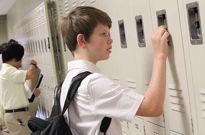 Unlike some of his classmates, Notre Dame Academy High School freshman Andrew Brautigan successfully conquers the combination lock on his new locker before his first class. Photo By Michael Alexander