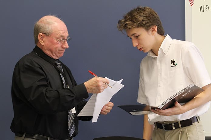 Symphonic Band instructor Bob Tolton shares some sheet music with Notre Dame Academy High School freshman Jared Darrow. Photo By Michael Alexander
