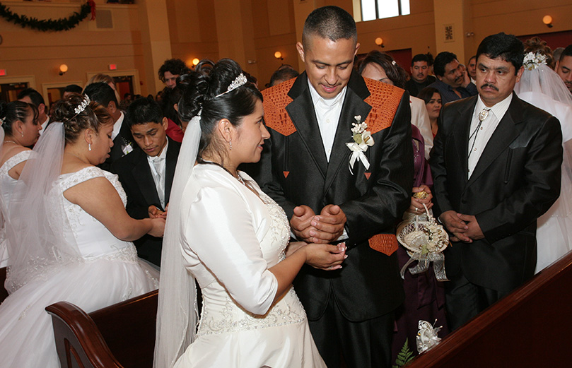 Groom Hector Fraire, second from right, presents 13 gold coins to his bride Gloria, a Latin and Mexican wedding tradition. The coins, blessed by the Father Jesús-David Trujillo during the ceremony, represent Jesus and his 12 disciples. Giving and accepting the coins is a sign of mutual trust and belief in one another. It also becomes a promise to one's new wife that he will support and care for her. Photo By Michael Alexander