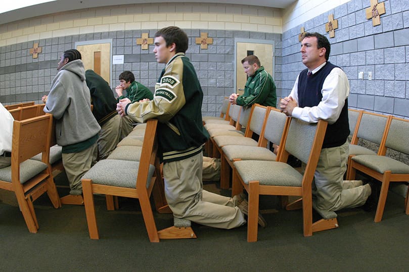 Four and half hours prior to the Feb. 1 game against Grady High School, the team gathers for a Mass in the school chapel. Theology instructor Father Augustine Tran was the main celebrant for the Mass. Kneeling on the outside are (l-r) senior guards Jordan Callahan and Sean Cunningham and head coach Brian Marks. Blessed Trinity went on to a 97-71 victory, but the consecutive win streak ended the next night at 22 after a 61-55 loss at Marist School. Photo By Michael Alexander