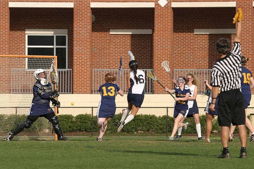 Marist School senior Catherine Beadles shoots the ball pass St. Pius defensive player Elizabeth Gallo (#13) and goalie Gillian McAllister for one of her three first period goals to help lead her team to a 12-6 victory over St. Pius X High School. Photo By Michael Alexander