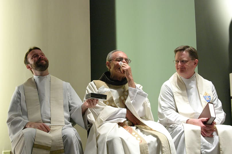 It is an emotional morning for Father Mario DiLella, OFM, center, as he celebrates his final Sunday liturgy after 38 years as the chaplain of the Georgia Tech Catholic Center. Father Kevin Hargaden, left, pastor of St. Peter Church, LaGrange, provides support and Kleenex during the occasion as Msgr. Joseph Corbett, vicar general of the Archdiocese of Atlanta, looks on. Father Hargaden is also a graduate of Georgia Tech and a former president of the Catholic Center community. Photo By Michael Alexander