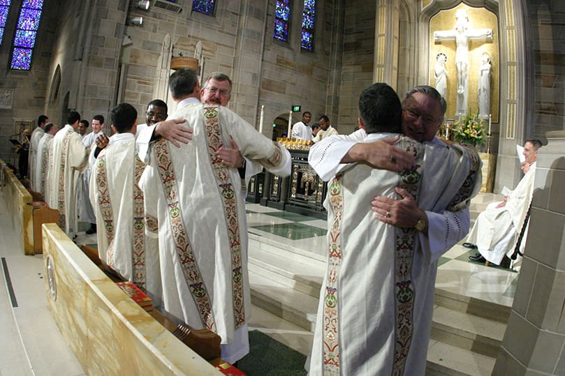 The Archdiocese of Atlanta's newest deacons are welcomed with a kiss of peace by their brother deacons to conclude the rite of ordination. Photo By Michael Alexander