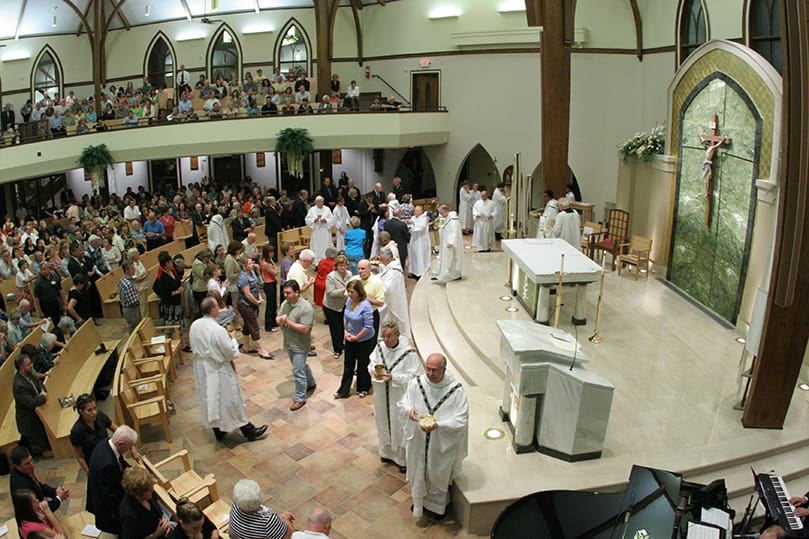 LaSalette priests Father Tom Leclerc, foreground center, chair of the religious studies department at Emmanuel College, Cambridge, Mass., and Father Roger Plante distribute holy Communion in the refurbished sanctuary at the Church of St. Ann's Marietta. Father Leclerc, a parochial vicar at the church from 1979-1984, served as liturgical consultant during the renovation project. Photo By Michael Alexander