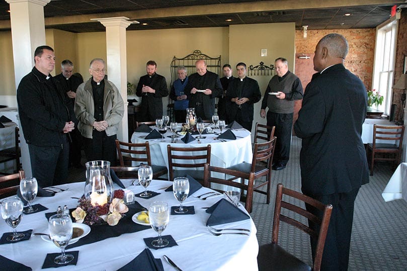 Archbishop Gregory leads the blessing before a group from of St. Lawrence Church and some other priests prior to a meal at the Lil' River Grill, Lawrenceville. Photo By Michael Alexander