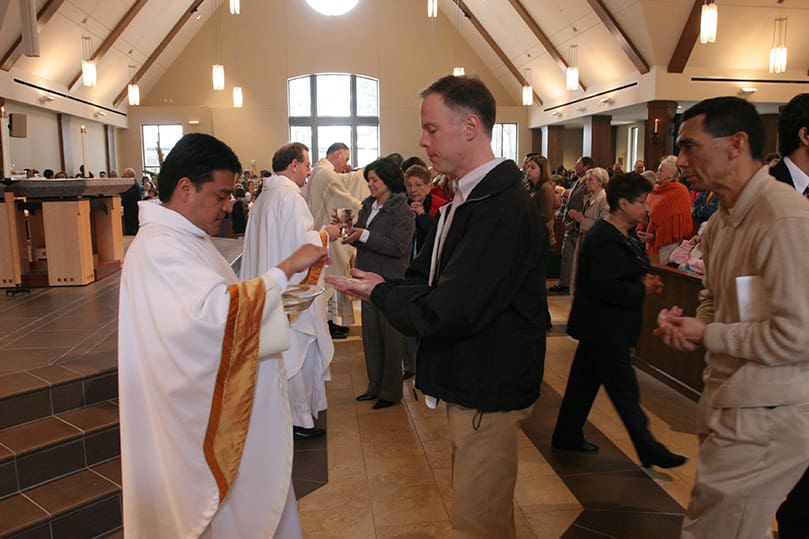 Immaculate Heart of Mary Church parochial vicar Father Juan Anzora distributes the body of Christ to parishioners on hand for the Mass of dedication. Photo By Michael Alexander