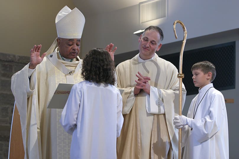 Archbishop Gregory recites the closing prayer as Immaculate Heart of Mary Church pastor stands at his side. The service, nearly three hours, marked the parish's first eucharistic celebration in its new church. Photo By Michael Alexander