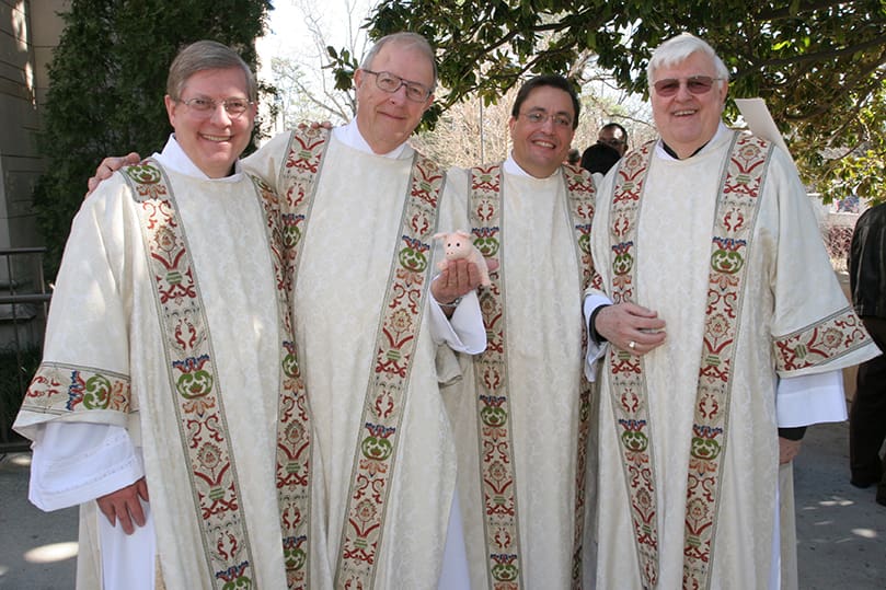 (L-r) Deacons James Tramonte, Stuart Mead and Jose Pupo join retired deacon of formation, Deacon Loris Sinanian following their Feb. 7 ordination to the permanent diaconate. Stuart is holding a small pig doll affectionately know as “Saint Baconi.” The pig became a class symbol of someone who gives their all. Photo By Michael Alexander