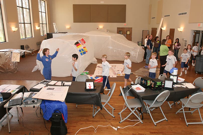 U.S. Space and Rocket Center education specialist Melissa Snider, left, ushers in a group of St. Jude School third-graders as they prepare to do additional work on a mock space station and make the solar panels. The USSRC is a NASA center for the public. Photo by Michael Alexander