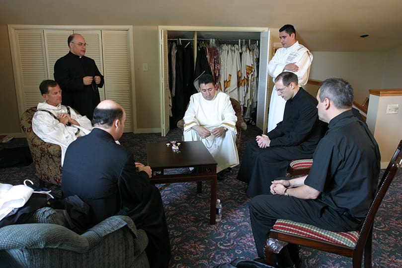 (Clockwise, from middle left) Father Brett Brannen, vice rector of Mount Saint Mary's Seminary, Emmitsburg, Md., joins ordination candidates Omar Loggiodice, Salomon Cortes, Ignacio Morales, Tim Gallagher, Brian Lorei, and Nicholas Azar as they recite the rosary in the Cathedral of Christ the King rectory prior to their June 27 ordination. Photo By Michael Alexander