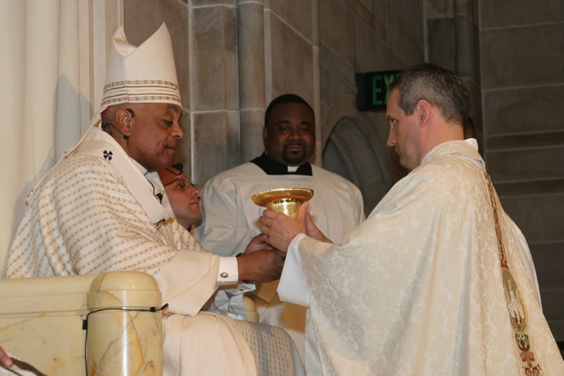Archbishop Gregory presents the chalice and paten to Father Brian Lorei. Photo By Michael Alexander