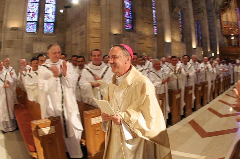 Bishop Luis Zarama is a bishop in motion as he makes his entrance to a thunderous applause up the center aisle of the cathedral to his place on the altar.