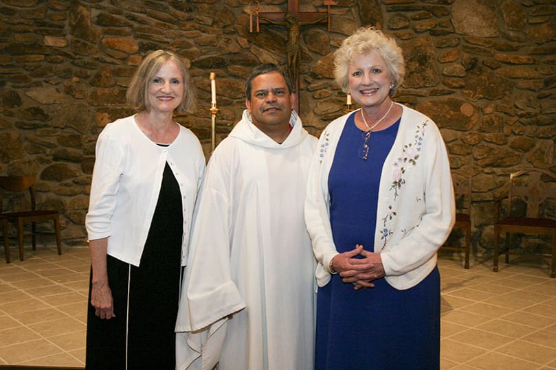 Sisters Mima Corbitt, left, and Mandy Mills, right, stand at the foot of the altar with Our Lady of LaSalette pastor Father Victor Reyes. Corbitt and Mills are offspring from one of the parish's founding families. Photo By Michael Alexander