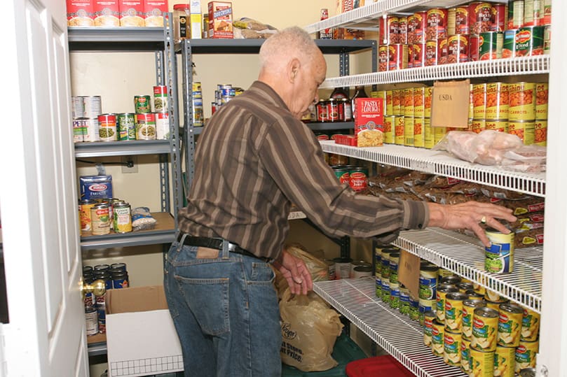 Senior volunteer Ulysses Hollis, Sr. bags up some canned goods for families inside The Sullivan Center food pantry. Photo By Michael Alexander