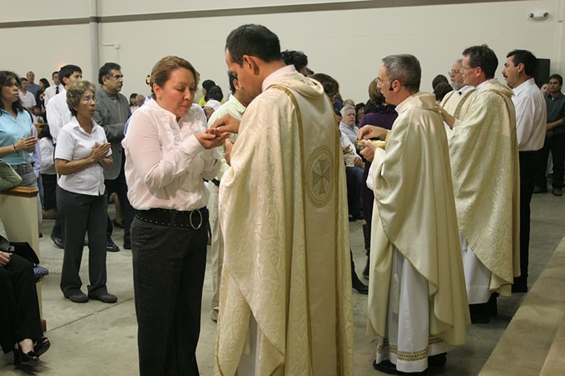 (Foreground to background) Father Pedro Poloche, chief advocate at the Atlanta Metropolitan Tribunal, Bishop Luis Zarama and Father John Durkin Jr., pastor of St. Monica Church, Duluth, distribute holy Communion during the Nov. 14 Mass of dedication. Photo By Michael Alexander