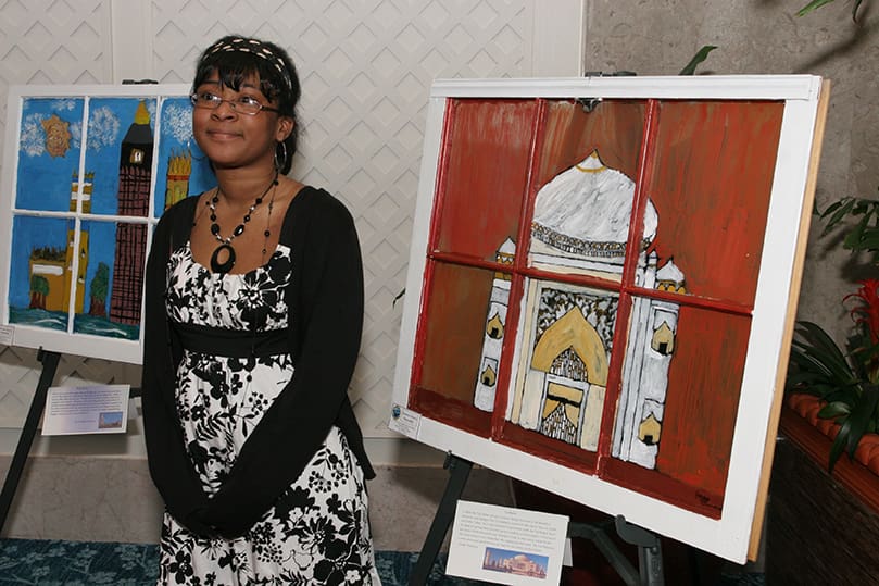 Jordy Timmons stands beside her painting of the Taj Mahal. Timmons was one of the 31 seventh grade artists from St. John the Evangelist School who participated in the 10th annual Windows Art Exhibit at the Renaissance Concourse Atlanta Airport Hotel, March 5. All of the art is framed with donated and recycled house windows. Photo By Michael Alexander