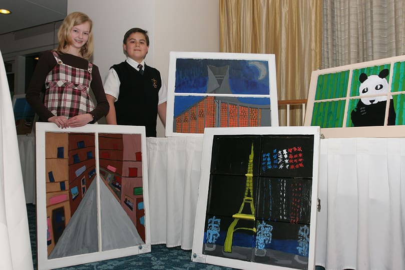 Laura Poole, left, and Ethen Lund stand with their paintings A Look at Paris and L'église Sainte-Jeanne-d'Arc, respectively. Poole painted one of the Paris streets she went down from a past visit to the city. Lund painted the historic church dedicated to St. Joan of Arc. He and his family had an opportunity to visit the church in 2001. Photo By Michael Alexander
