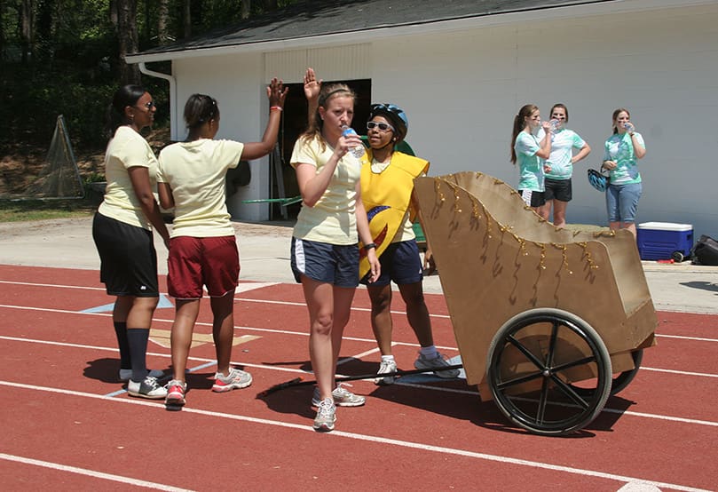 The gold faction, The Golden Girls, of (foreground, l-r) Mikela Gordon, Danielle Neal, Lilly Sullivan and Diana Destin celebrates its victory over the green faction, The Green Mean Fighting Machine, following the second heat of Chariot Race 2010. Photo By Michael Alexander
