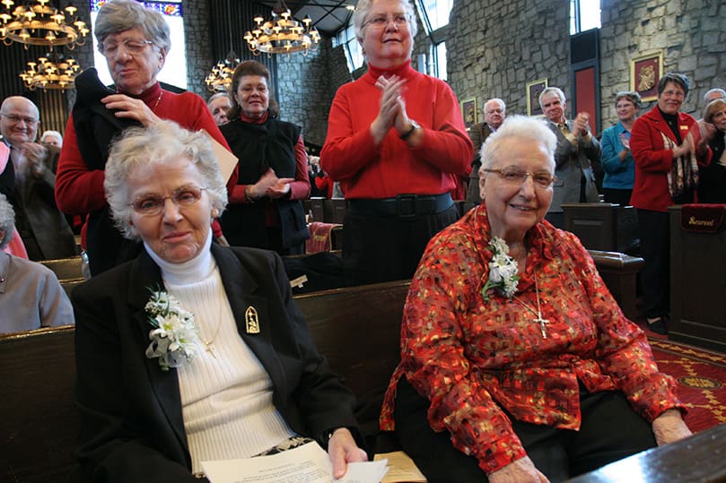 The Grey Nuns of the Sacred Heart Sister Sally White, left, and Sister Eileen Murray receive a standing ovation from the congregation at St. Jude the Apostle Church, Atlanta, following Msgr. James Fennessy's homily. Photo By Michael Alexander