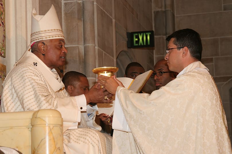 As a sign of the new priest's office, Archbishop Gregory presents the chalice and paten to Father Mario Lopez. Photo By Michael Alexander