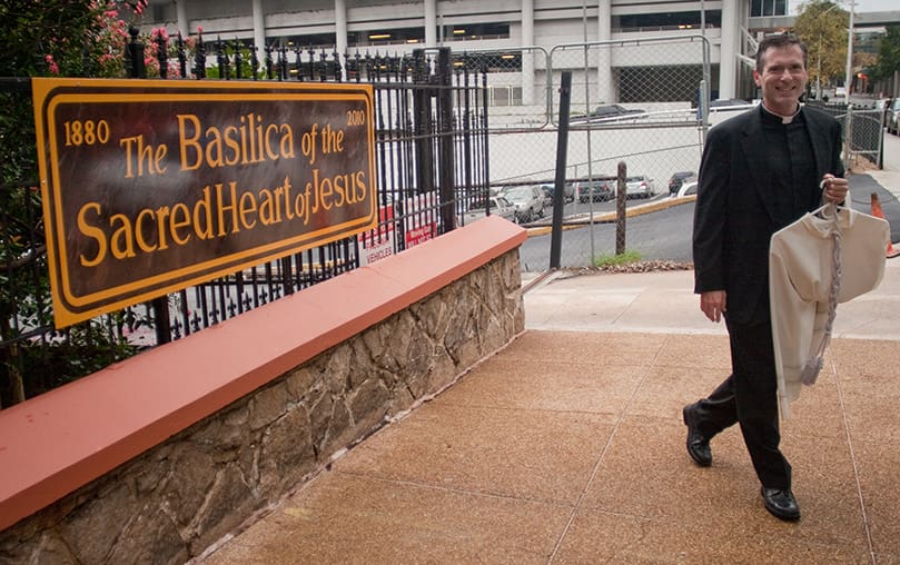 Father Luke R. Ballman, director of vocations for the Archdiocese of Atlanta, walks past the new sign in front of Sacred Heart. Photo by Thomas Spink