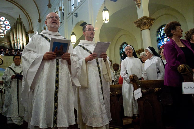 Former Sacred Heart pastor, Father Steven Yander (left) and Father Patrick Scully process in with other priests as women religious and members of the congregation look on. Photo by Thomas Spink