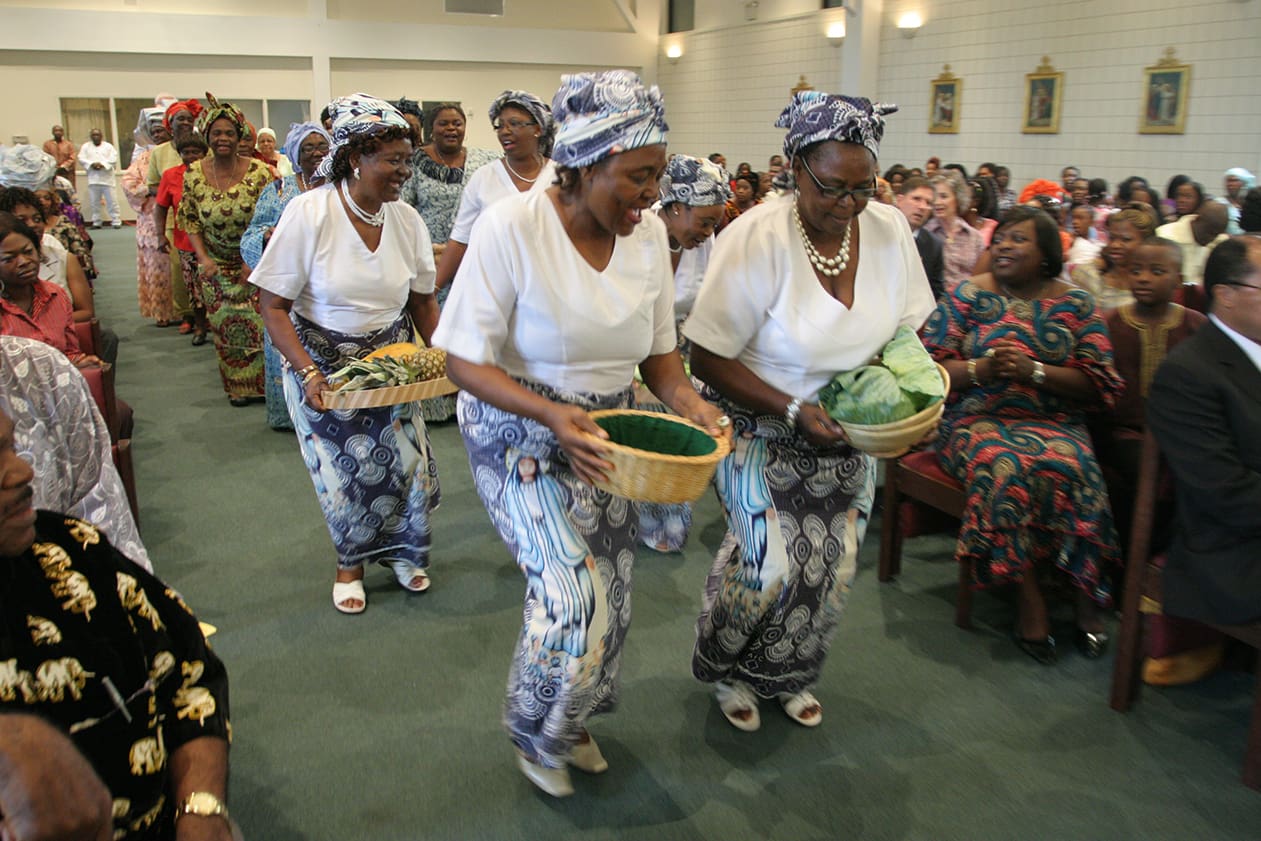 Members of the Catholic Women Association of Cameroon lead the offertory procession down the center aisle of Mary Our Queen Church. Photo By Michael Alexander