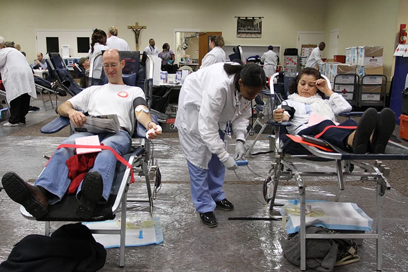 American Red Cross blood collection technician Lasha Carter, center, checks on Guillermina Coronado's blood bag as Brian Arnberger, left, reads during his donation process. Photo By Michael Alexander