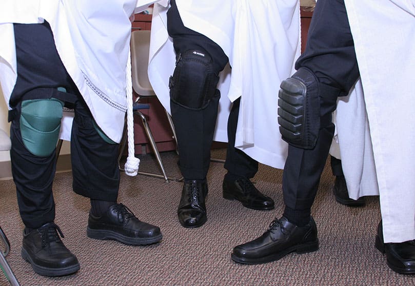 Showing off their various knee pads, ordination candidates (l-r) Fernando Barrueta, Dave Thomasberger and Curtis Marsh came prepared for all the kneeling required on the cathedral's marble floor during the rite of ordination. Photo By Michael Alexander