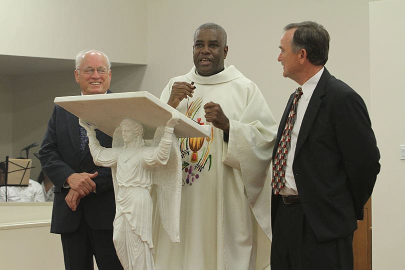Missionaries of St. Charles - Scalabrinians Father Jacques Fabre, administrator of San Felipe de Jesus Catholic Mission, center, extends his thanks to Catholic Construction project manager Dick Jenson, left, and the architect Charles Saunders, There were smiles when Father Fabre announced to the congregation that the $1.1 million project realized a $300,000 savings. Photo By Michael Alexander