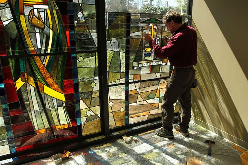 Frei installs the middle panel of the Coat of Arms window. Photo By Michael Alexander