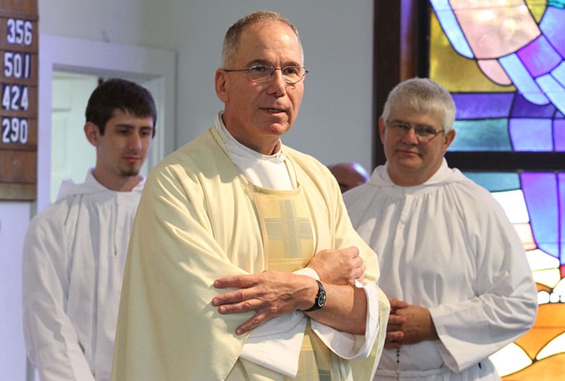 As the last daily Mass at the Cantonment Chapel comes to an end, Father Fred Wendel gives some closing remarks before the final blessing. Standing behind him are altar servers Joey Buchieri, left, and his father Mike, a retired Army lieutenant colonel whose family has worshipped at the chapel since 1990. Photo By Michael Alexander