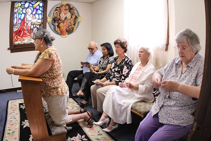 (Clockwise from left) Susana Burdeshaw (kneeling), Charles Rickmond, Lee Anderson, Felipa Bonoan, Janina Kresyman and Angela Quirke pray the rosary prior to the final Sunday Liturgy. Over the years they gathered to say the rosary on the first Sunday of each month and every Sunday during the months of May and October. Photo By Michael Alexander