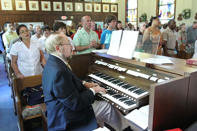 The congregation sings as Michael Kingsbury plays the organ. Kingsbury was the Cantonment Chapel organist for 30 years. Photo By Michael Alexander