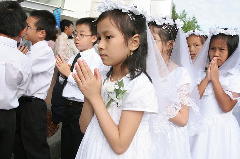 Nine-year-old Lananh Nguyen, center, lines up with fellow first communicants before the morning procession gets underway.  Photo By Michael Alexander