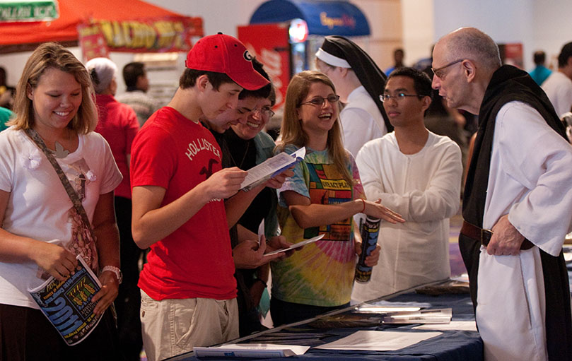 Brother Elias Marechal, far right, vocations director for the Monastery of the Holy Spirit, Conyers, speaks with curious youth at the Monastery's booth, June 25. Photo by Thomas Spink