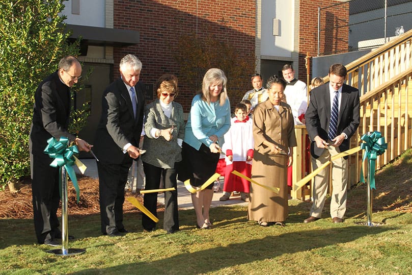 Ribbon cutting participants included (l-r) Legionaries of Christ Father Robert Presutti, LC, head of school, Doug Tollett, chairman of the board of directors and his wife Brenda, Madeliene Flanagan, principal of the Lower and Middle Schools, My Thi Huynh, the teacher who has taught in the Lower School the longest, and Andy Barfield, project manager for New South Construction. Families, students, faculty, staff and Pinecrest Academy board of directors gathered on the grounds of the new John Paul II Lower School Activities Building for its Oct. 4 dedication. Photo By Michael Alexander