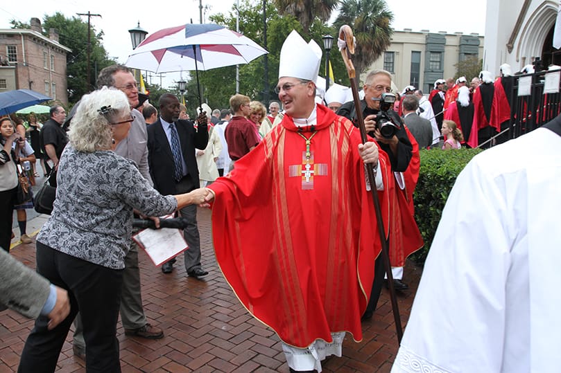 Bishop Gregory John Hartmayer, the new Bishop of Savannah, greets one of the many pedestrians along the sidewalk in front of the Cathedral of St. John the Baptist as he leaves his Oct. 18 episcopal ordination. Photo By Michael Alexander  