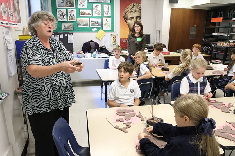 Teacher Leslie Coy, left, provides instructions to her fourth grade art class as they make magnolias with clay. Coy was a teacher assistant for 10 years before she became a full time teacher in 1991.