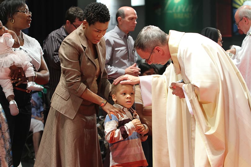 Bishop Luis Zarama, auxiliary bishop of Atlanta, extends a blessing to four-year-old Chetachi Iro as his mother Chi looks on during the opening Mass of the 2012 Eucharistic Congress. Photo By Michael Alexander