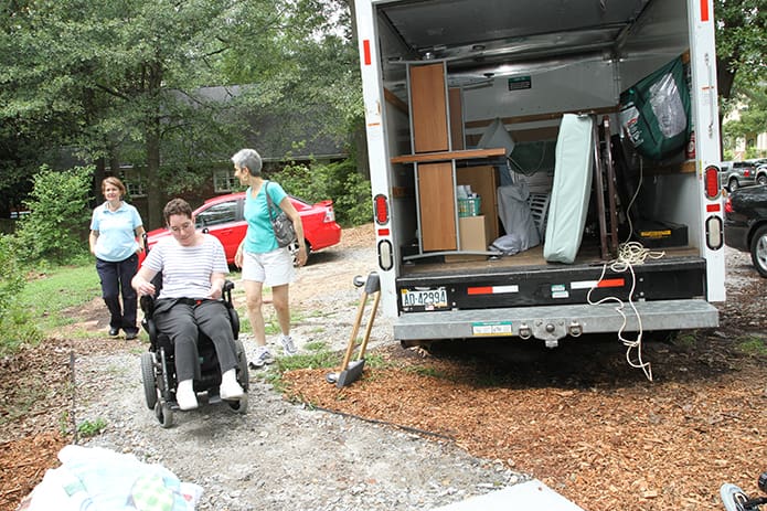 Laura Swenson rolls by the U-Haul truck holding her possessions as she makes her way to the entrance of the house. Photo By Michael Alexander