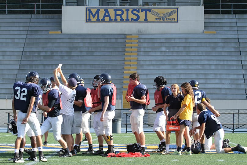 Running backs coach Michael Coveny, fourth from left, coordinates the “scout team” offense so they can run a pass play against the Marist defense. Photo By Michael Alexander