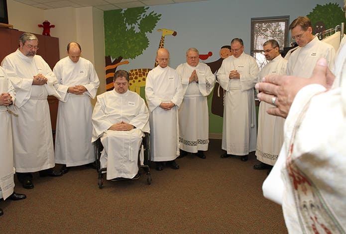 Prior to the ordination, permanent diaconate candidates (l-r) Joseph Crowley, Jerome Hayward, Francis Head Jr., Earl Buckley, James Harkins, Mark Friedlein, Carlos Garcia and Thomas Sandusky stand in silence as Deacon Dennis Dorner, director of the permanent diaconate, leads a prayer. Photo By Michael Alexander