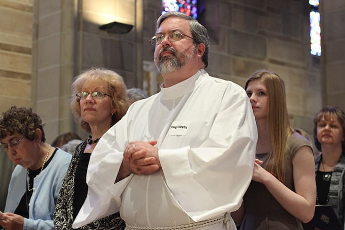 Permanent deaconate candidate Joseph Crowley stands in the pew next to his wife of 29 years, Donna, during the Feb. 2 ordination at the Cathedral of Christ the King, Atlanta. Photo By Michael Alexander
