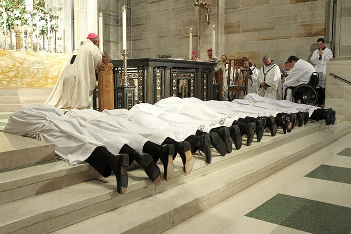 The twelve ordination candidates prostrate themselves on the altar at the Cathedral of Christ the King during the Litany of the Saints. Photo By Michael Alexander