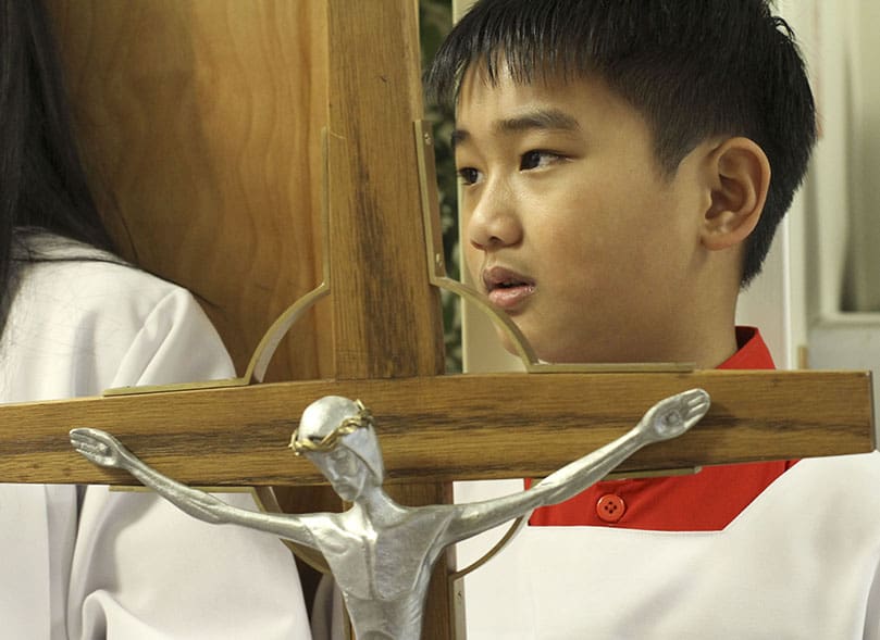Eleven-year-old Patrick Vu prepares to lead the liturgical procession into the Holy Vietnamese Martyrs Church, Norcross, December 1. Photo By Michael Alexander