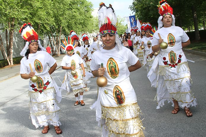 Mariana Carreno, center, of St. Brendan the Navigator Church, Cumming, leads a group of Hispanic dancers from her parish in the morning procession.