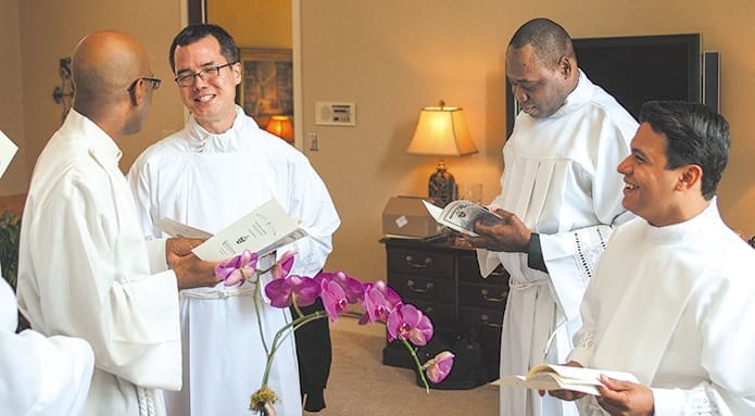 L-r) Desmond Drummer, Brian Baker, Junot Nelvy and Rey Pineda relax and look over the programs before the Mass and their ordinations to the transitional diaconate.