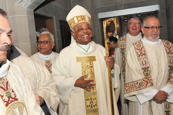 Archbishop Wilton D. Gregory smiles as he’s totally caught off guard by the presence of two best friends from out of town. The two priests showed up unannounced for the Jubilarian Mass, which also marked the archbishop’s 40th anniversary as a priest. Photo by Michael Alexander